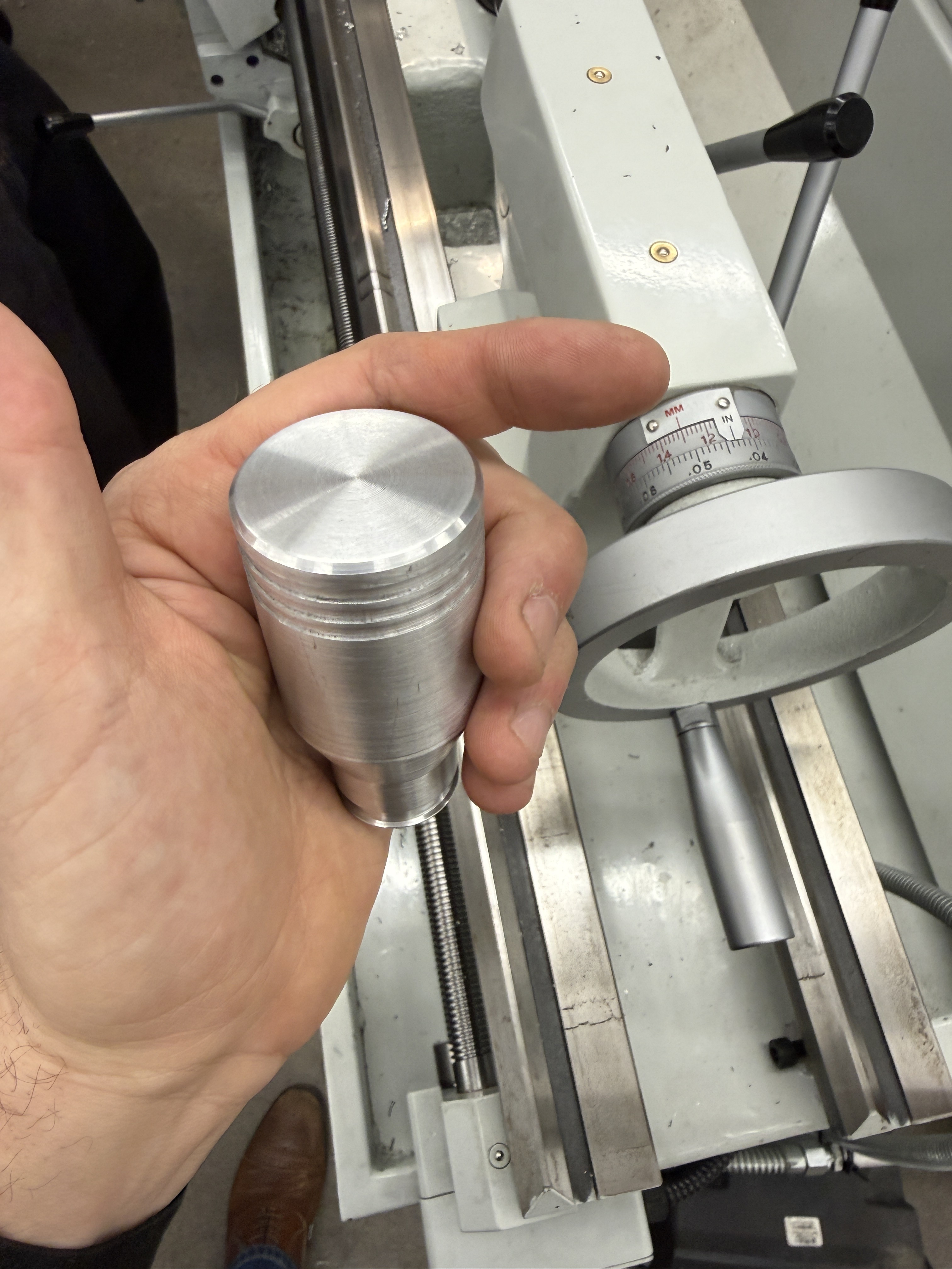 Machined aluminum cylinder in front of a metal lathe