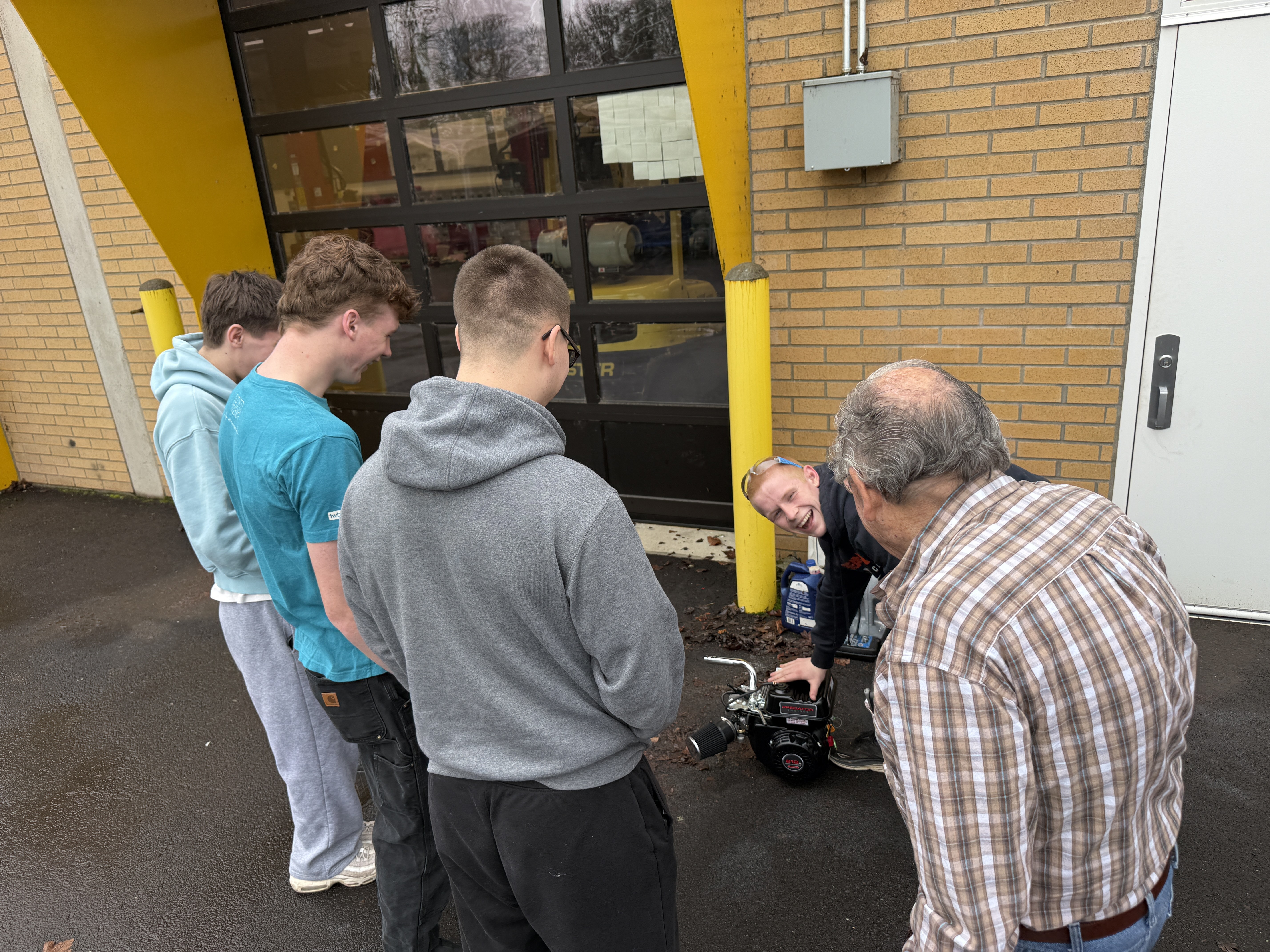 Students and instructor examining a small engine outside