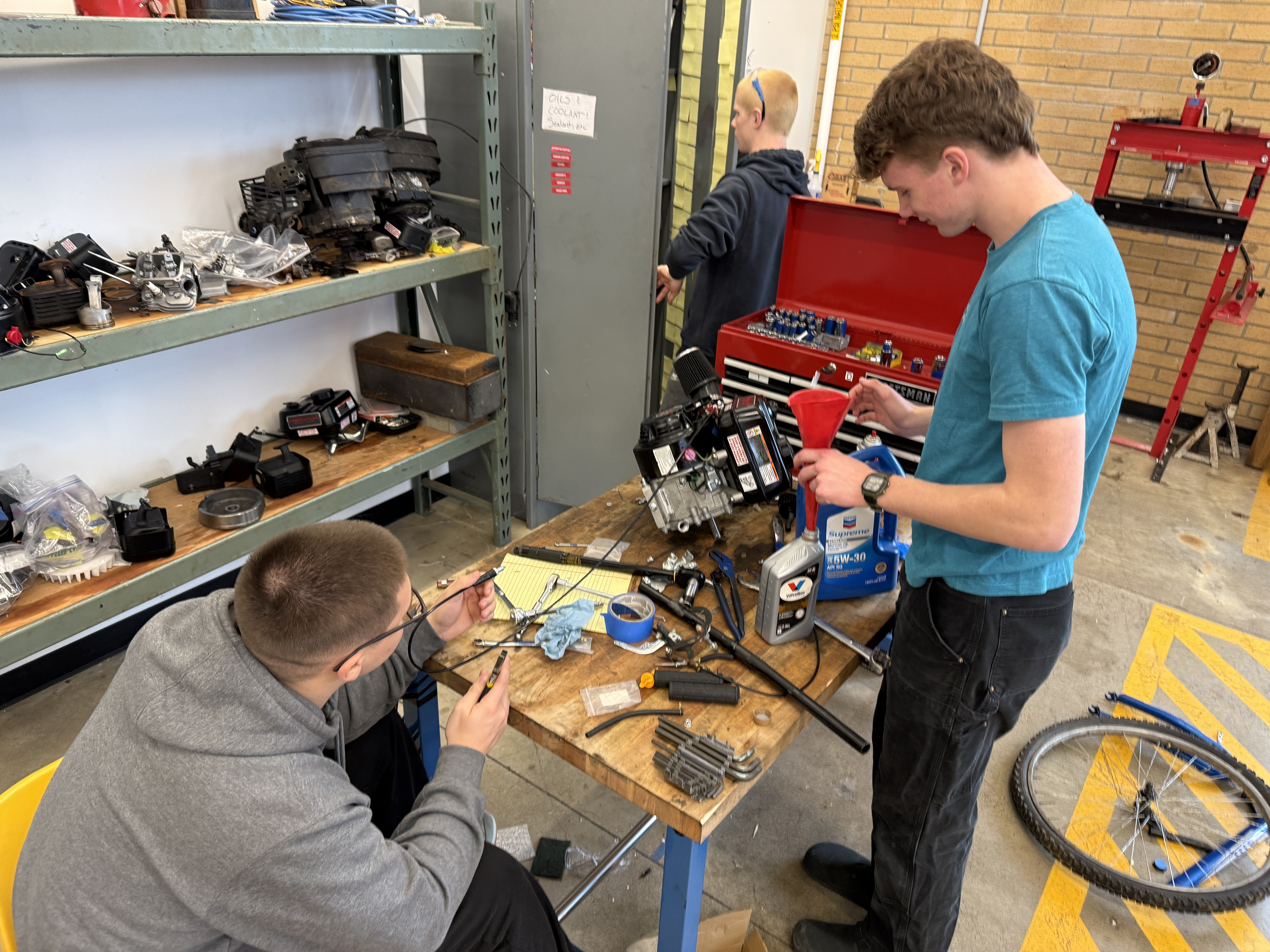 Two students working on an engine teardown at a workbench